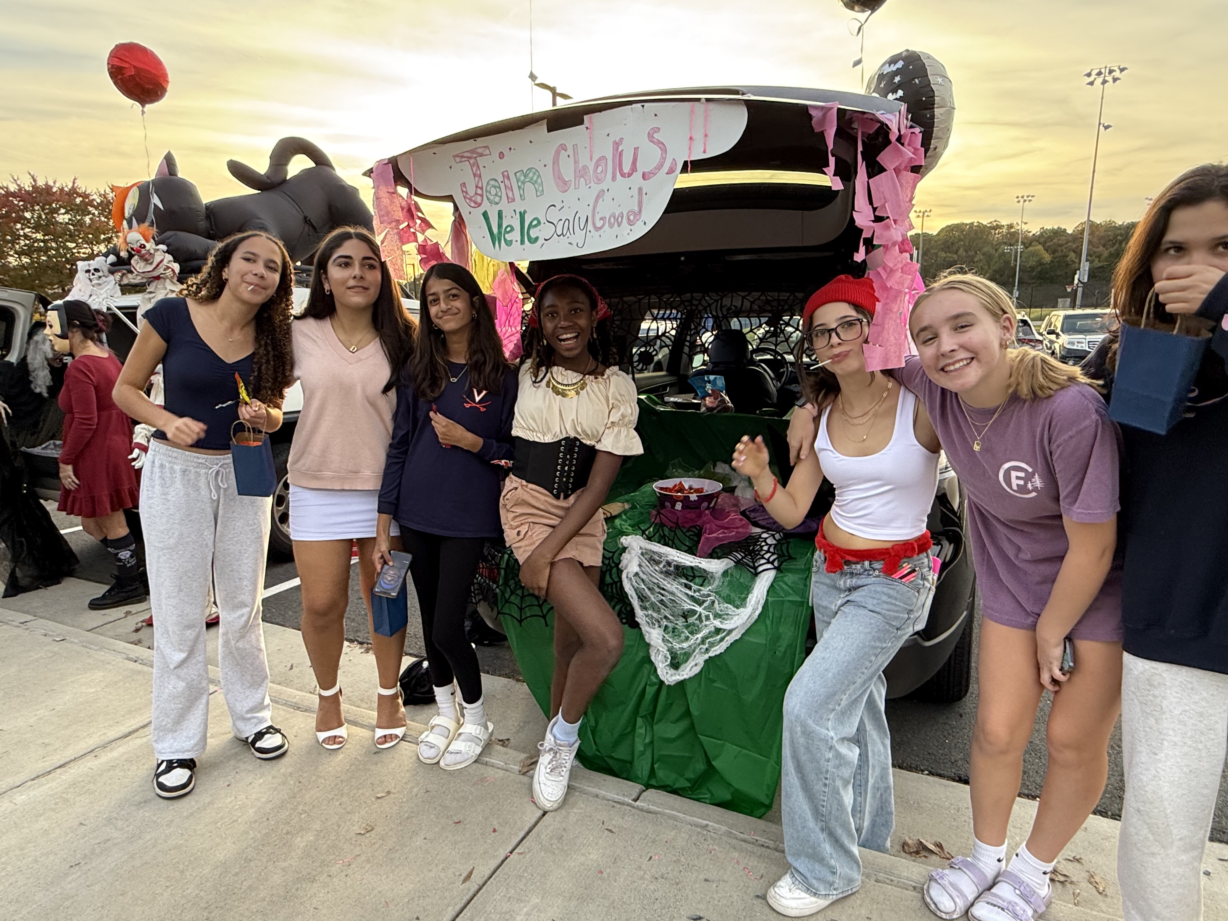 Hughes chorus students pose in front of the decorated trunk or treat car that they sponsored