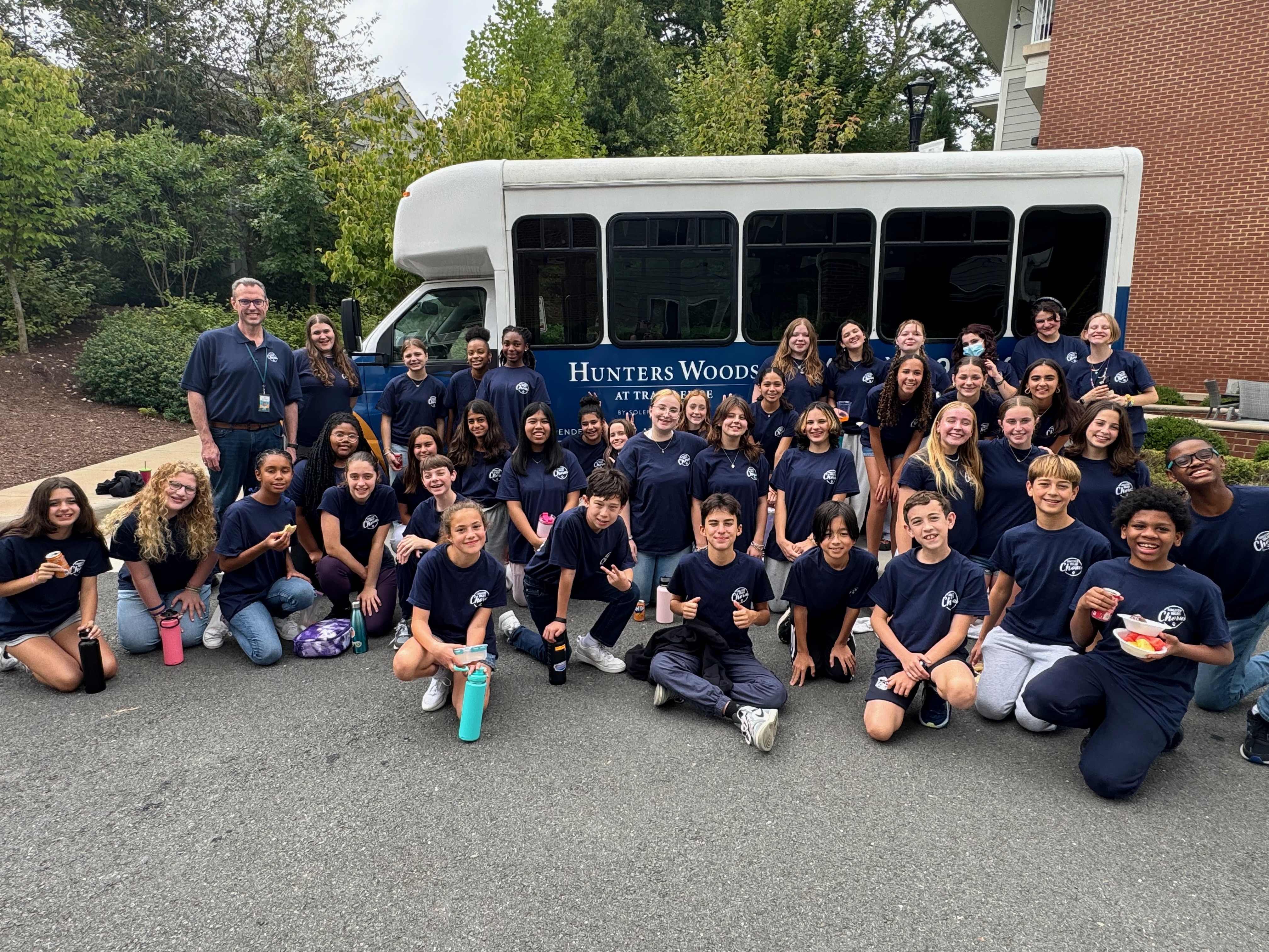 Hughes chorus students pose in front of bus after performing at Hunters Woods Senior Living Facility 